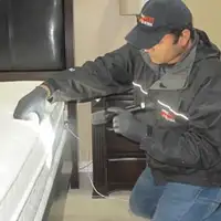 Bed bug inspection technician checking a mattress and bed frame for signs of infestation in Rockford, IL