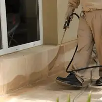 General pest control technician spraying exterior perimeter around a home in Rockford, IL